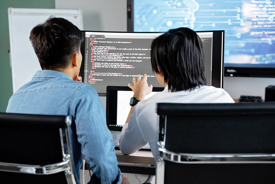 Dva developera zajedno raspravljaju o kodu na ekranu